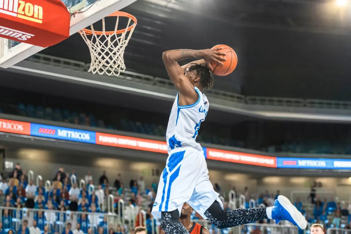 Basquetebol: Jogador salta para marcar cesta. Desporto de equipa e competição.
