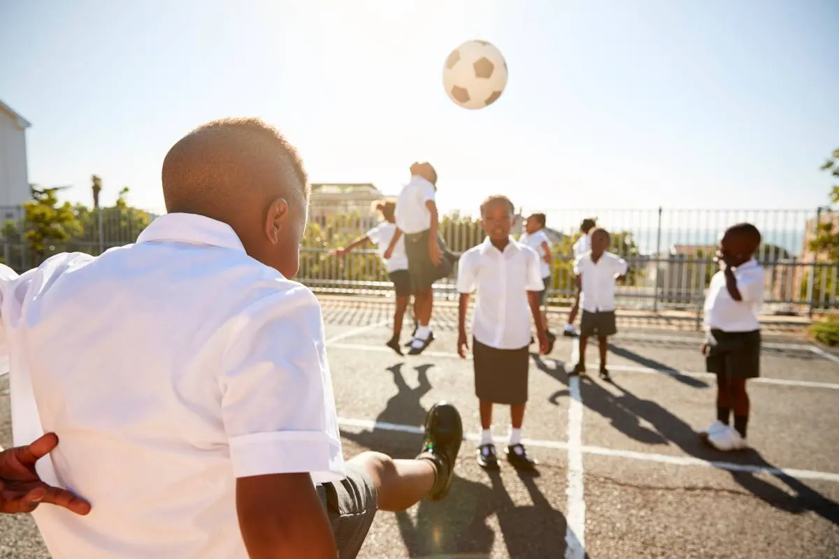 Crianças jogando kickball ao ar livre. Jogo de bola com regras e segurança. Esporte infantil divertido.