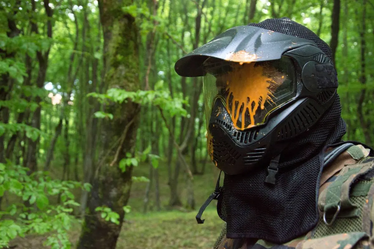 Jogador de paintball com máscara suja de tinta. Segurança no paintball.